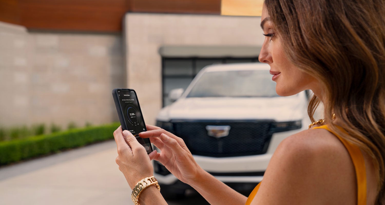 lady checking her mobile with a Cadillac vehicle background | Cole Valley Cadillac in Warren OH